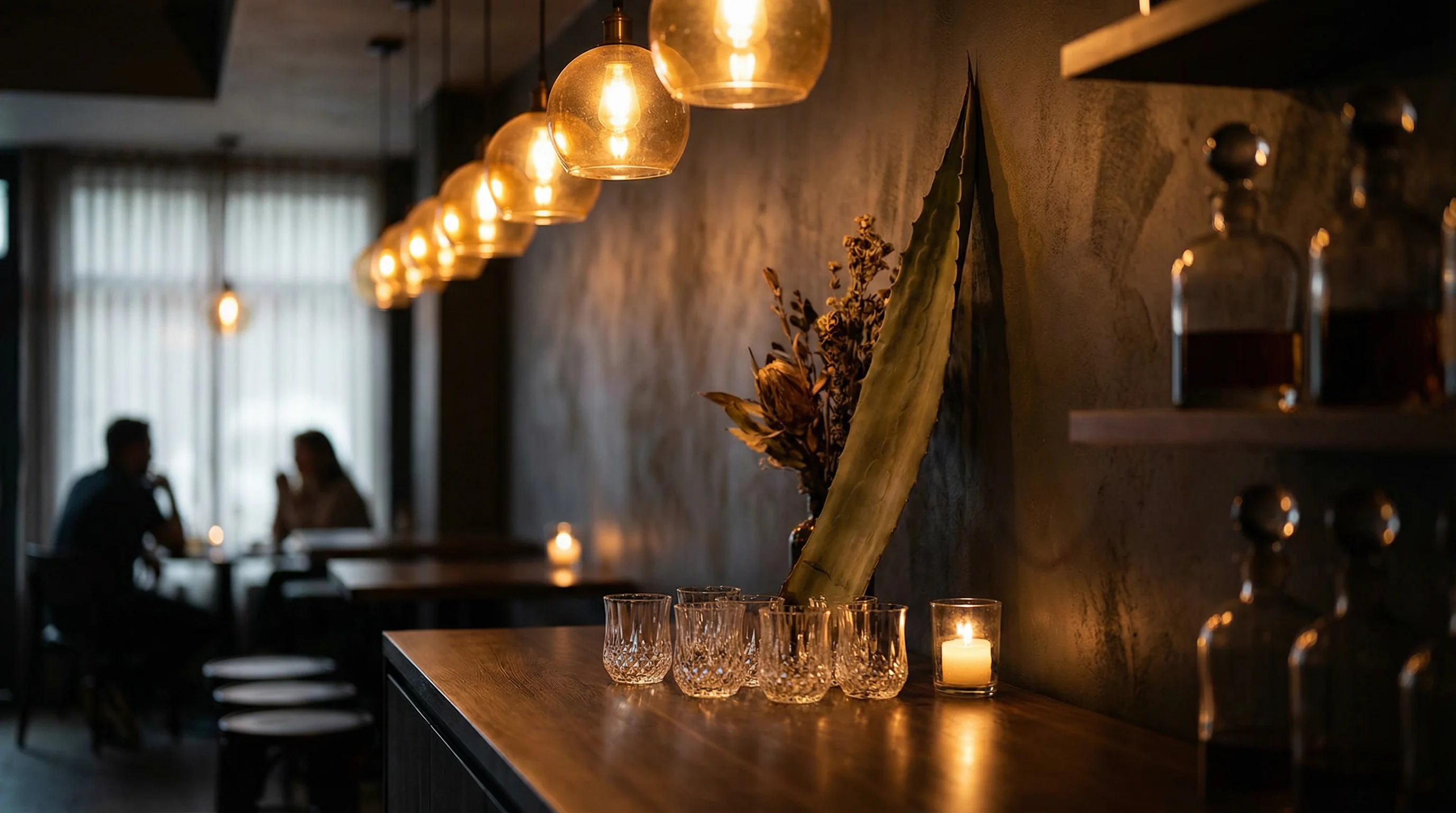 Intimate tasting bar counter with warm amber lighting and agave glassware arranged for a guided session